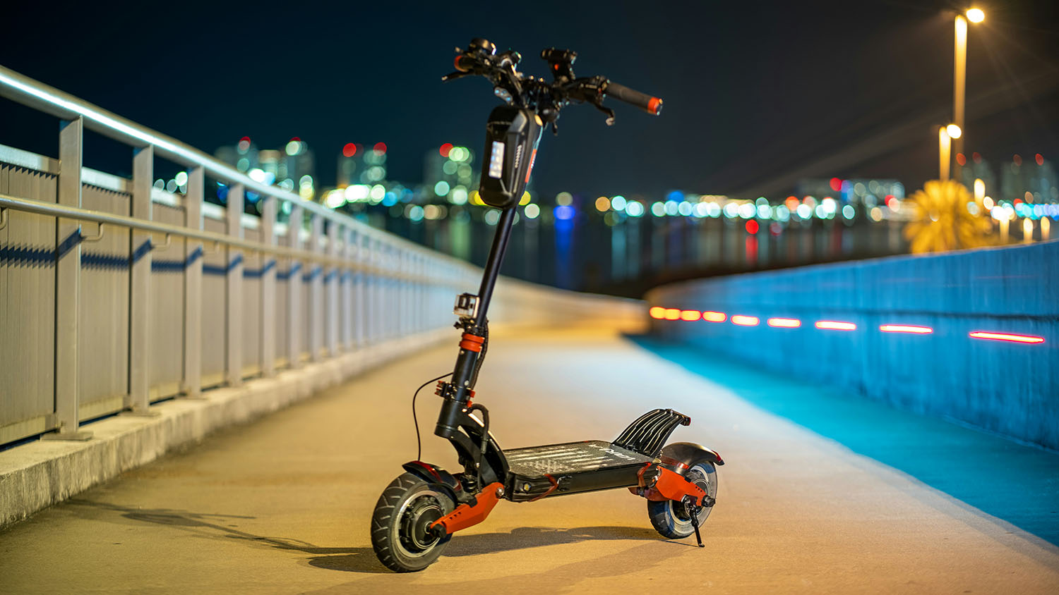A wet electric scooter is parked on a bridge at night. Scooter Advice