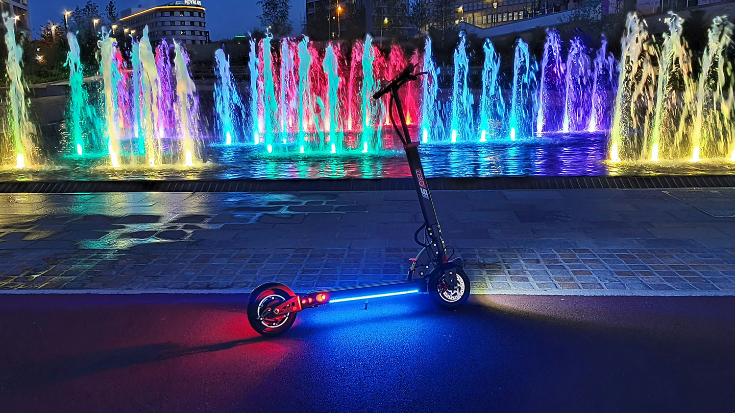 A colorful scooter with lights in front of a fountain. Can Electric Scooters Go Uphill? Scooter Advice