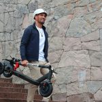 A man effortlessly carrying an electric scooter up some steps, demonstrating the ease of uphill mobility. can you take an electric scooter on a plane. Scooter Advice 360
