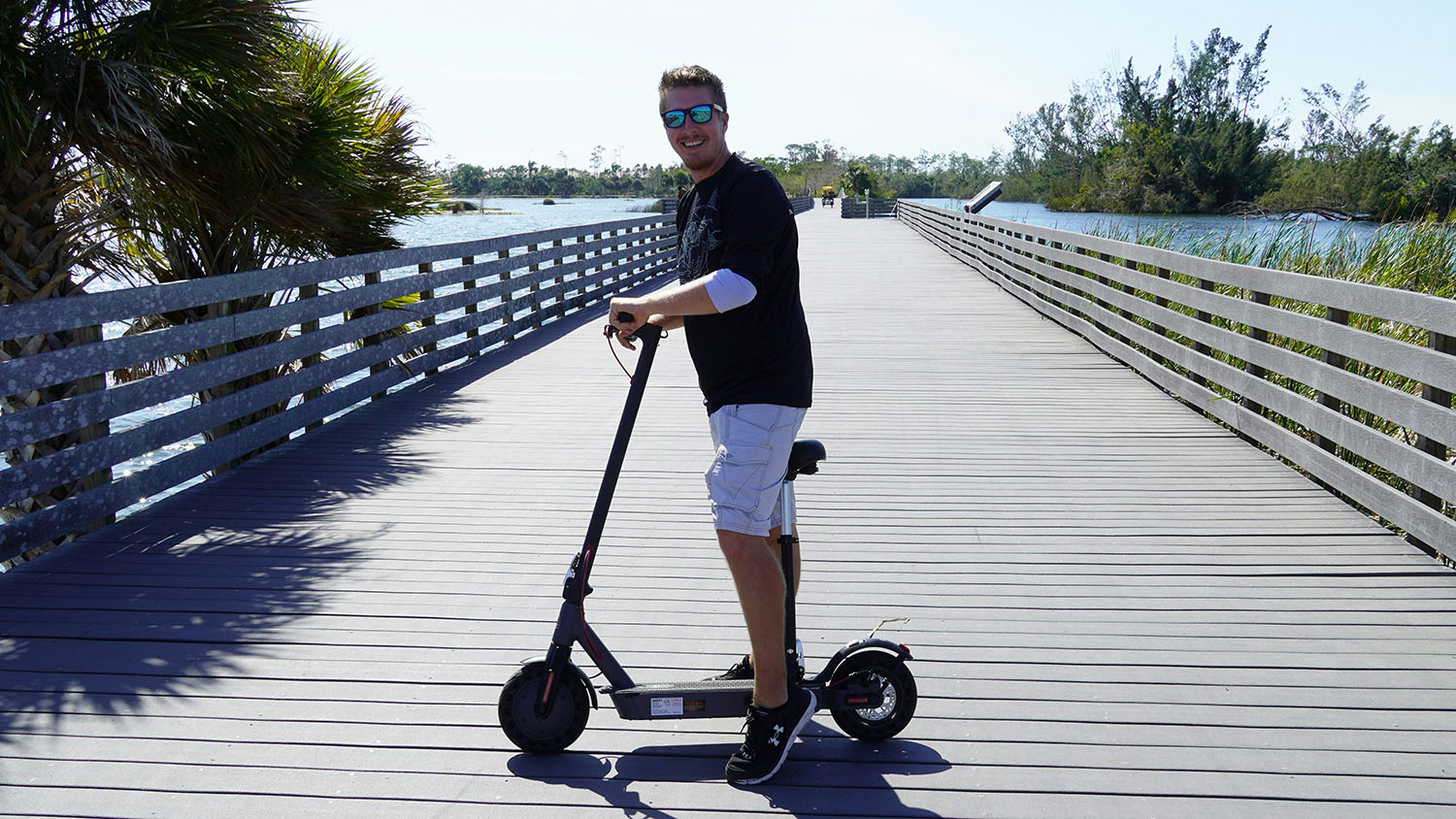 A man riding an electric scooter on a bridge, showcasing the convenience and eco-friendliness of electric transportation options. Scooter Advice