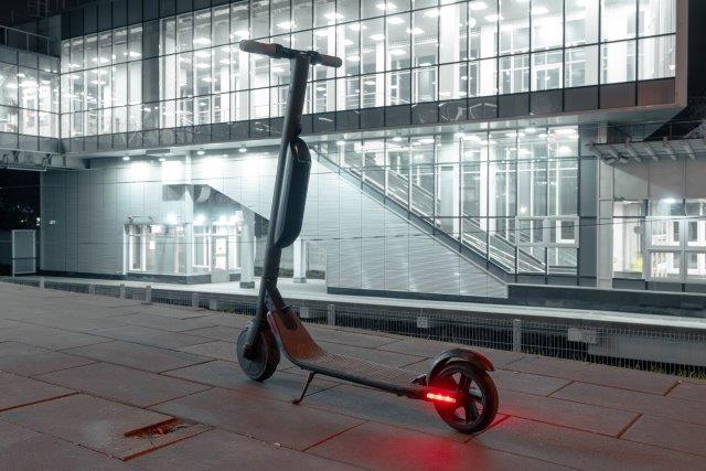 An electric scooter is parked in front of a building at night. How Long Do Electric Scooters Last? Scooter Advice 360