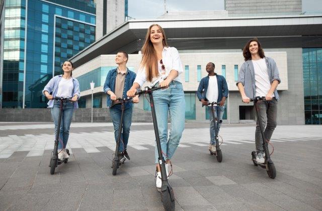 A group of people riding electric scooters in a city. Scooter Advice 360