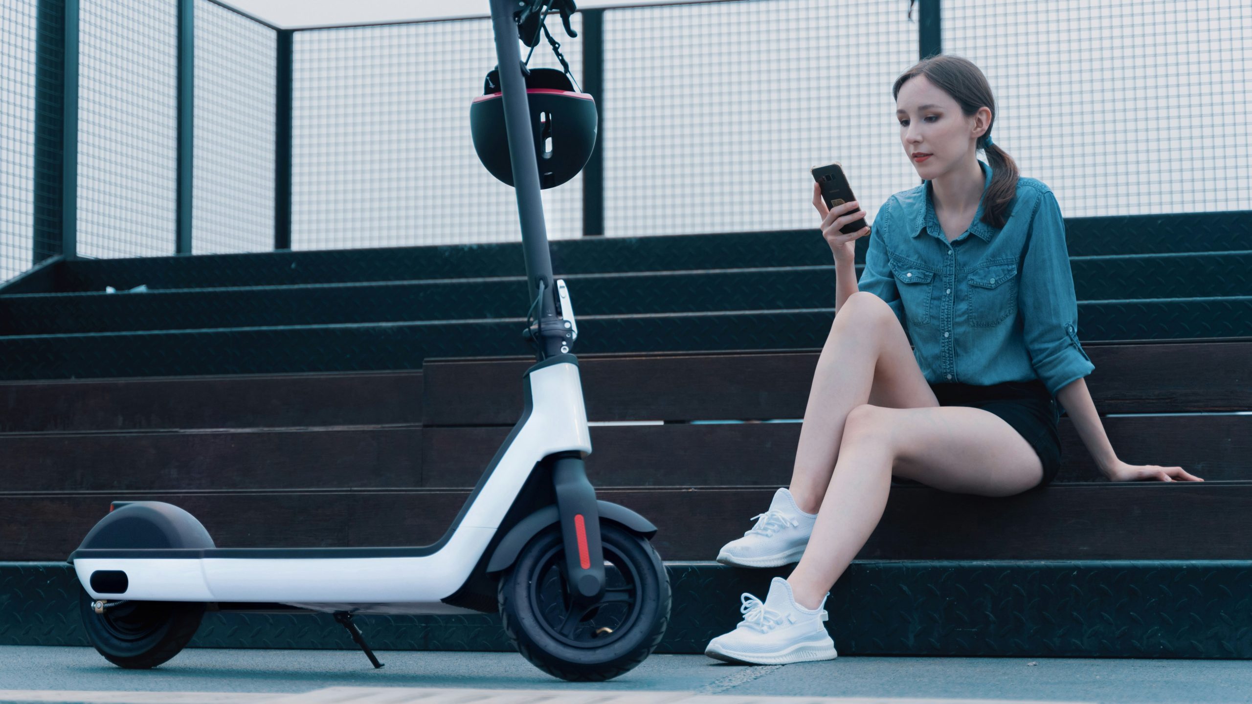 A woman sitting on a scooter while checking her phone for the price of a segway. Scooter Advice