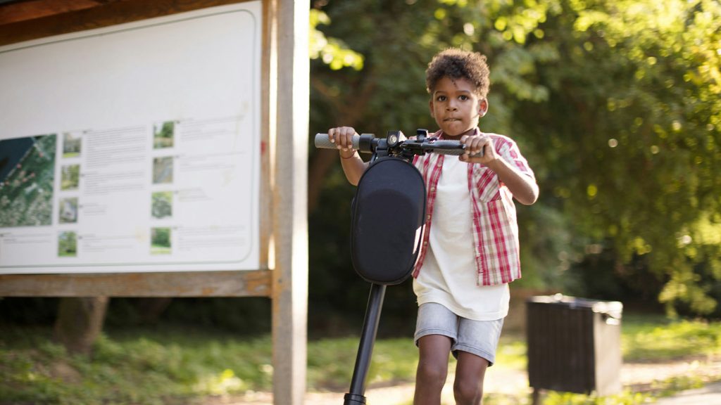 A young boy on an electric scooter in a park, wondering about the cost of a Segway. Scooter Advice