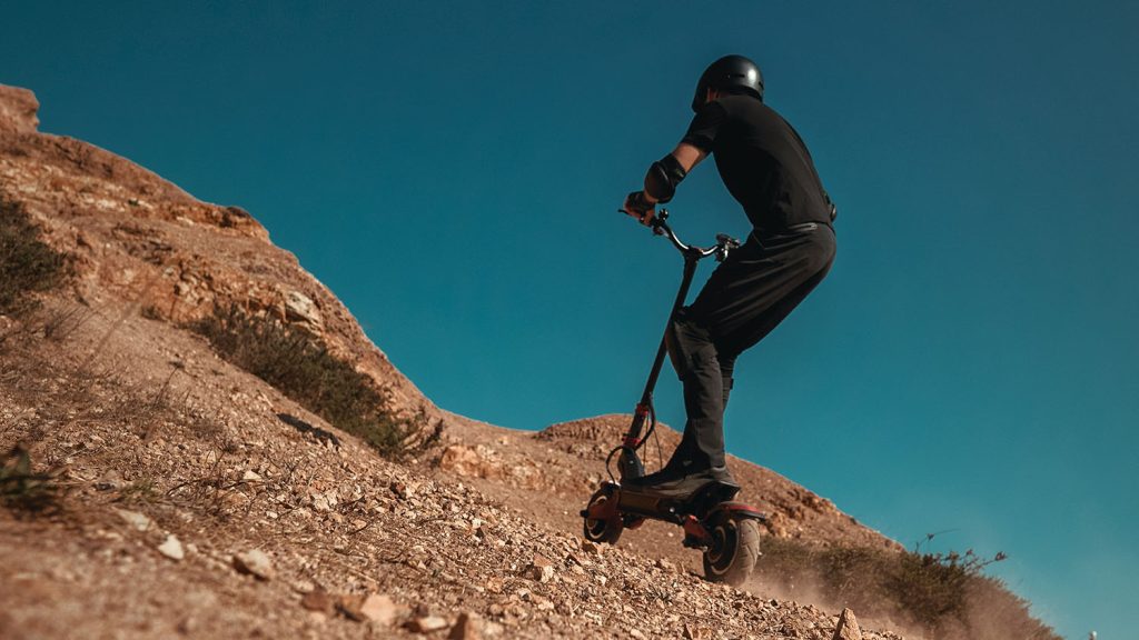 A person riding an electric scooter down a hill, showcasing the best off road electric scooter. Scooter Advice 360