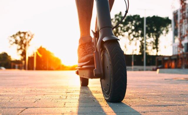 A person riding an electric scooter at sunset. Scooter Advice 360
