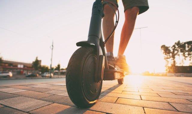 A person riding an electric scooter at sunset. When Did Electric Scooters Come Out. Scooter Advice 360