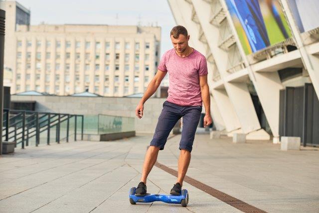 Man riding a hoverboard in an urban setting. Scooter Advice 360