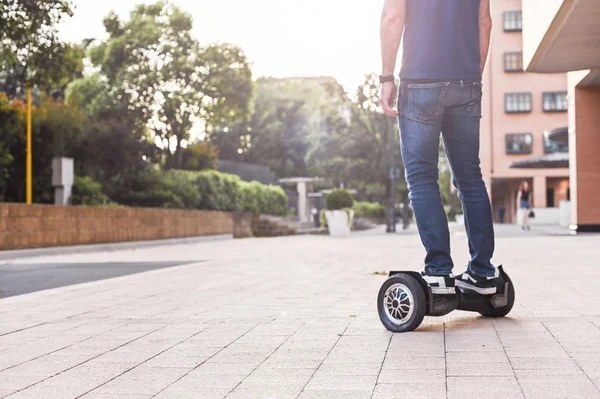 Person riding a hoverboard on a sunny campus pathway. Scooter Advice 360