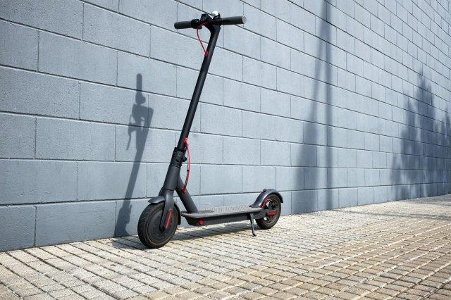A black scooter leaning against a wall. Scooter Advice 360