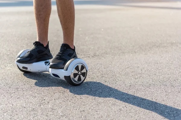 Person standing on a hoverboard on an asphalt surface. Scooter Advice 360