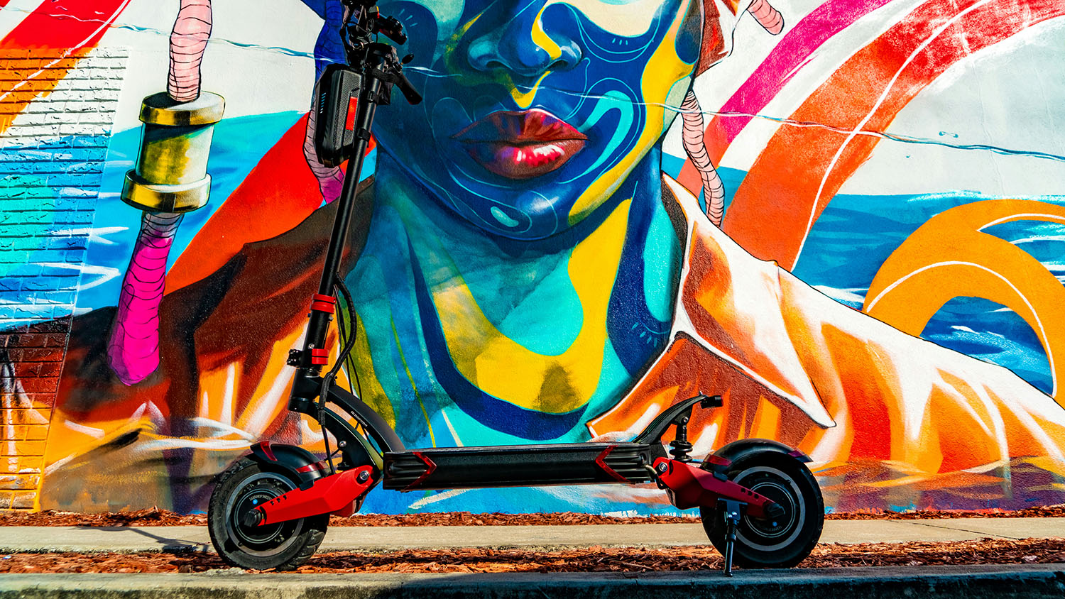 An electric scooter is parked in front of a vibrant mural. Scooter Advice