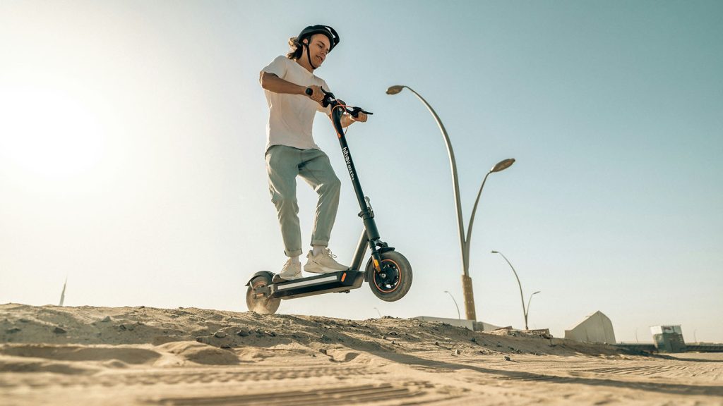 A man enjoying a ride on an electric scooter in the desert, wondering how long the charge will last. Scooter Advice