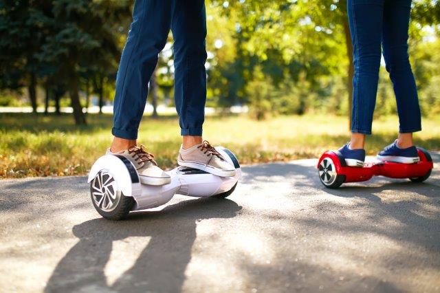 Two people using hoverboards outdoors on a sunny day. Scooter Advice 360