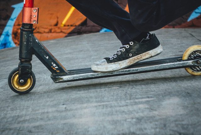A person riding an electric scooter with sneakers on it. Scooter Advice