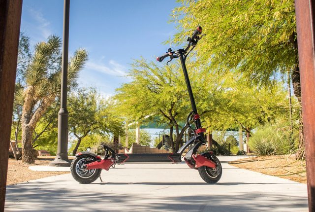 A red and black scooter is parked on a sidewalk. Scooter Advice