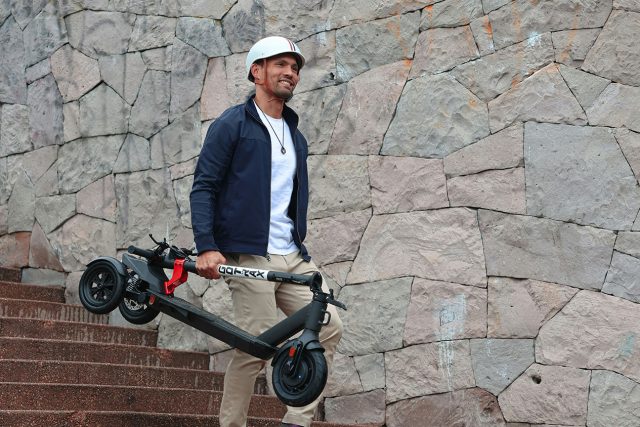 A man effortlessly carrying an electric scooter up some steps, demonstrating the ease of uphill mobility. can you take an electric scooter on a plane. Scooter Advice 360