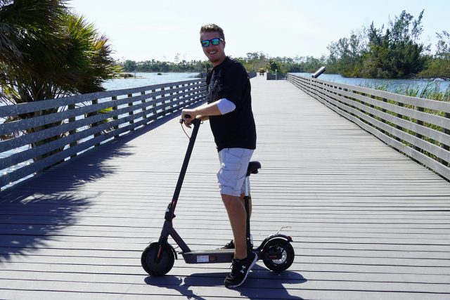 A man riding an electric scooter on a bridge. Can You Ride Electric Scooters on the Sidewalk? Scooter Advice