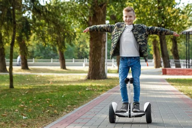 A boy is riding a segway in a park. Scooter Advice