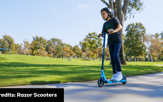 A person riding a blue scooter in a park, demonstrating how fast does the razor electric scooter go. Scooter Advice