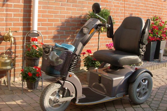 A motorized scooter is parked in front of a brick house. Scooter Advice